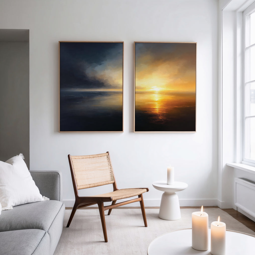 A modern living room with a light gray sofa, wooden chair, and small round table features the "Storm’s Edge - Set of 2" canvas prints on the wall and several lit candles for a cozy ambiance.