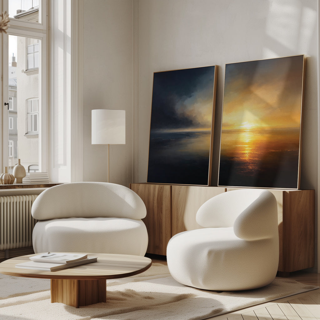 A modern living room with two white armchairs, a low wood coffee table, a floor lamp, and Storm's Edge - Set of 2 canvas prints leaning against a wooden sideboard by the window.