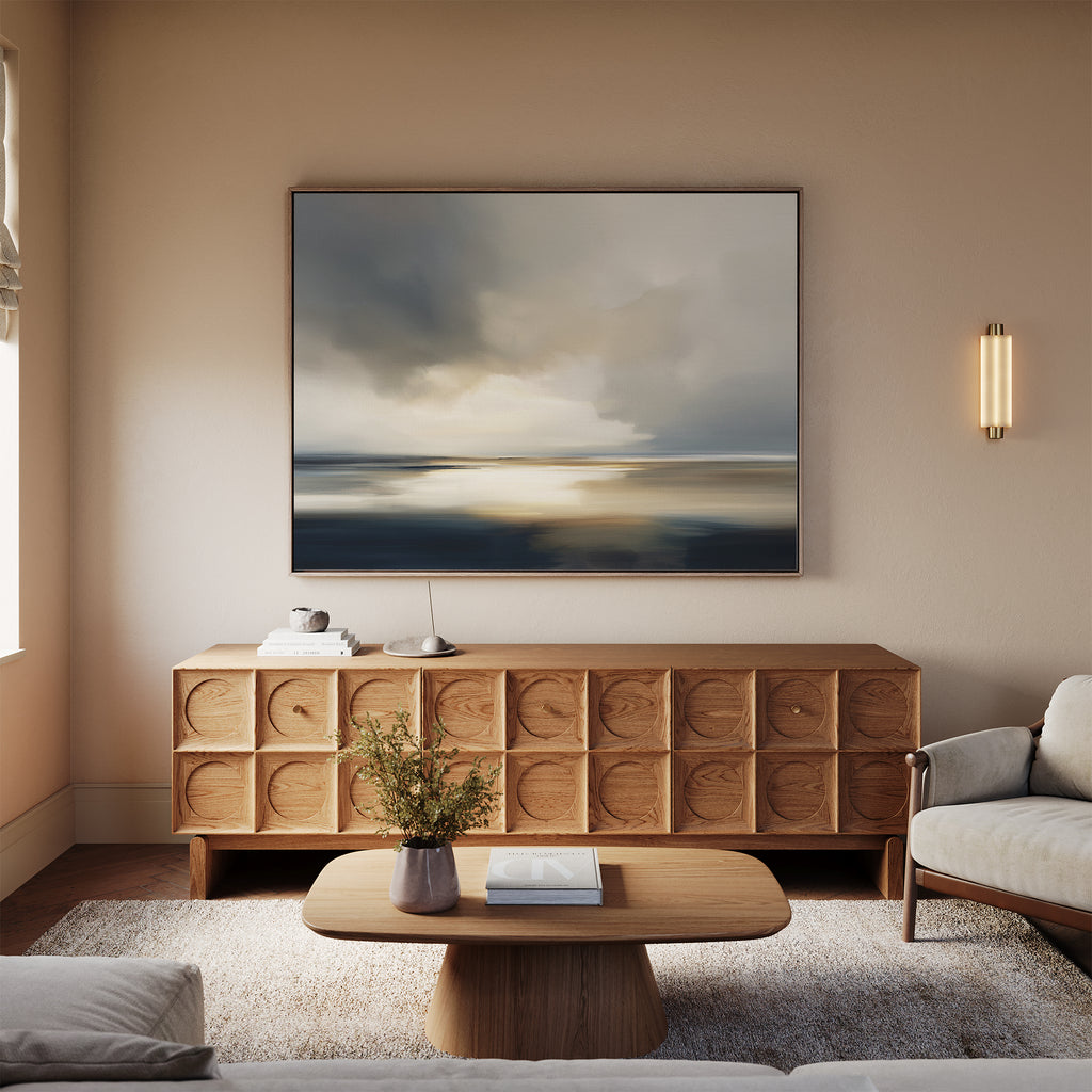 A modern living room with a beige sofa and rug, wooden coffee table, and sideboard. Above the sideboard, coastal elegance shines through the Stormy Tides Canvas Art - Horizontal, illuminated by soft natural window light.