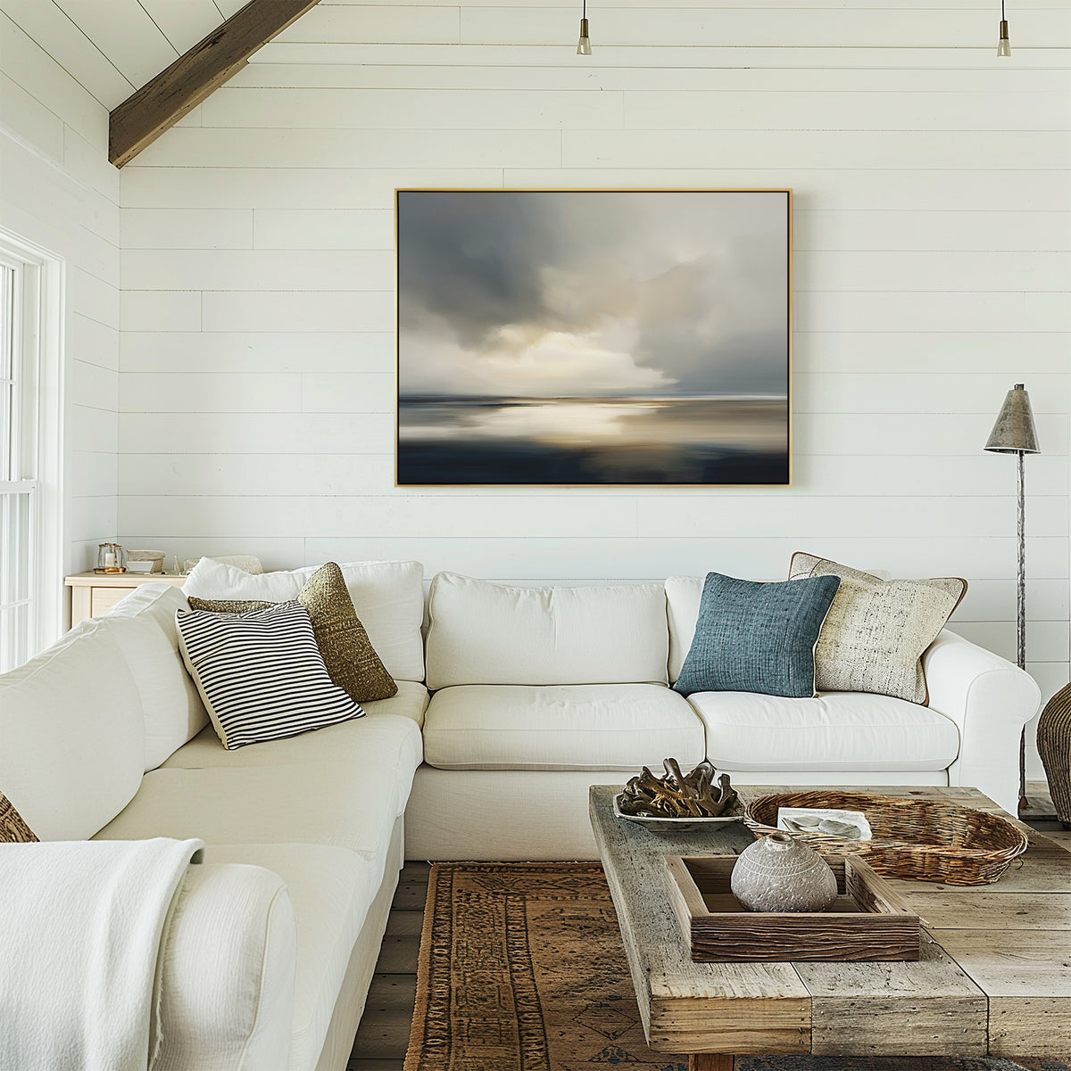 A bright, airy living room with white shiplap walls, a large white sectional, rustic wooden coffee table, and the Stormy Tides Canvas Art - Horizontal above the couch adds coastal elegance to the space.