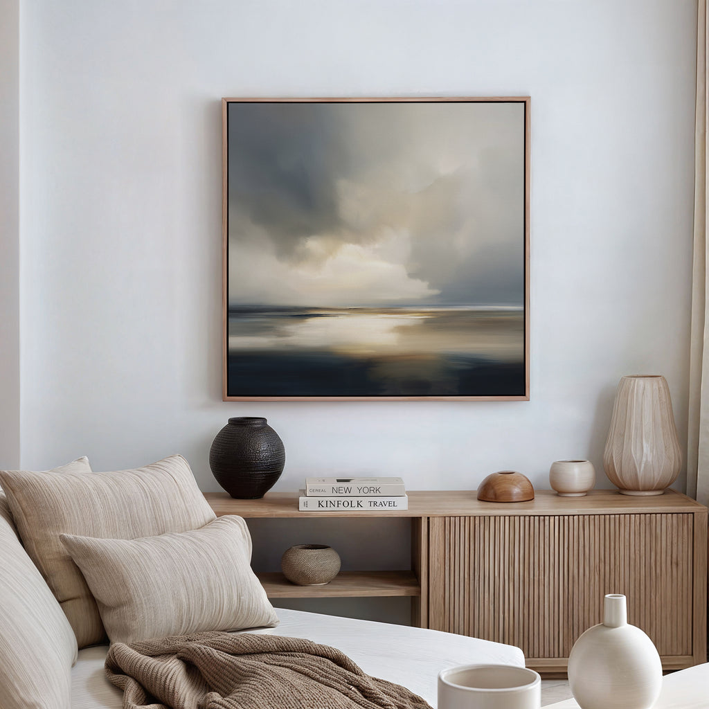 A cozy, modern living room with a beige sofa, neutral cushions, a wooden sideboard adorned with vases and books, and the Stormy Tides Canvas Art - Square, inspired by Nordic Park, creating a striking focal point on the wall.