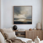 A cozy, modern living room with a beige sofa, neutral cushions, a wooden sideboard adorned with vases and books, and the Stormy Tides Canvas Art - Square, inspired by Nordic Park, creating a striking focal point on the wall.