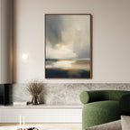 A modern living room features a green curved sofa, marble bench, and neutral walls. The Stormy Tides Canvas Art - Vertical in soft blue, gray, and beige tones adds a serene touch to this Nordic Park-inspired space with a minimalist vase of dried branches.