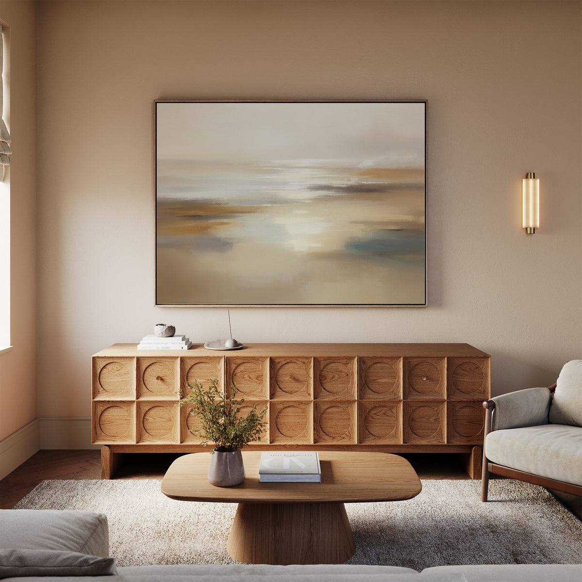 A modern living room with neutral tones features a wooden sideboard topped by the Sunlit Waters Canvas Art - Horizontal, a round coffee table with a vase, and light-colored furniture on a soft rug.