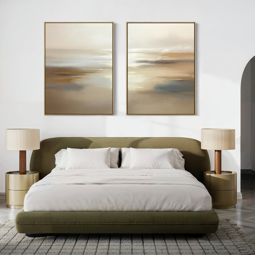 A modern bedroom featuring an olive green upholstered bed, white bedding, two beige and gold nightstands with matching lamps, a gray patterned rug, and "Sunlit Waters - Set Of 2" artwork above the bed.