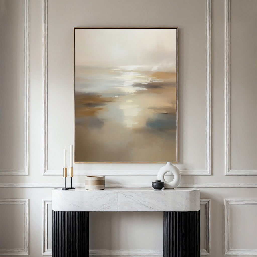 A modern console table with decor stands against a cream-paneled wall, topped by the Sunlit Waters Canvas Art – Vertical, featuring neutral hues of beige, white, and gold for a calm, elegant vibe with sophisticated wall art.