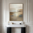 A modern console table with decor stands against a cream-paneled wall, topped by the Sunlit Waters Canvas Art – Vertical, featuring neutral hues of beige, white, and gold for a calm, elegant vibe with sophisticated wall art.