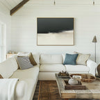 A cozy living room with a white sectional sofa, assorted throw pillows, a wooden coffee table with decor, and the Tempest Brewing Canvas Art - Horizontal displayed on a white shiplap wall beneath streaming natural light.