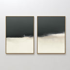 The Tempest Brewing - Set Of 2 features dramatic wall art with dark gray tops, light cream bottoms, and soft blurred edges. Thin gold frames add elegance to these pieces displayed side by side against a white wall.