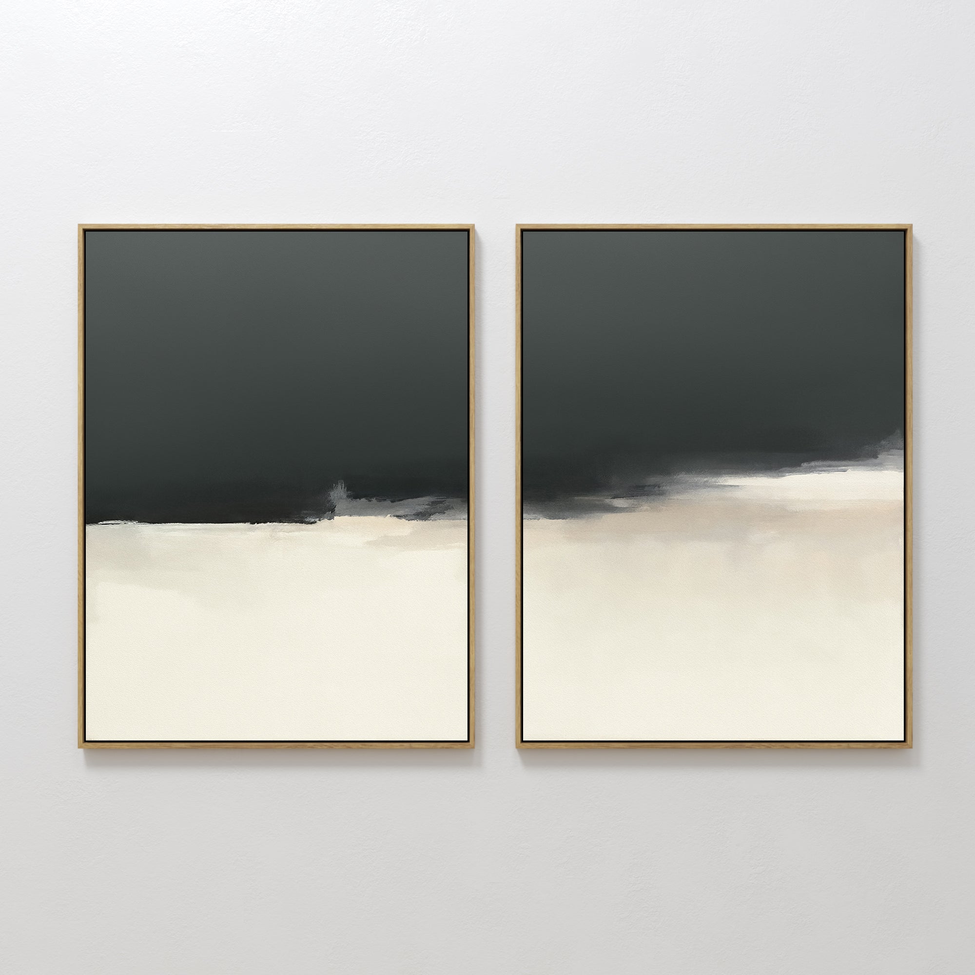 The Tempest Brewing - Set Of 2 features dramatic wall art with dark gray tops, light cream bottoms, and soft blurred edges. Thin gold frames add elegance to these pieces displayed side by side against a white wall.