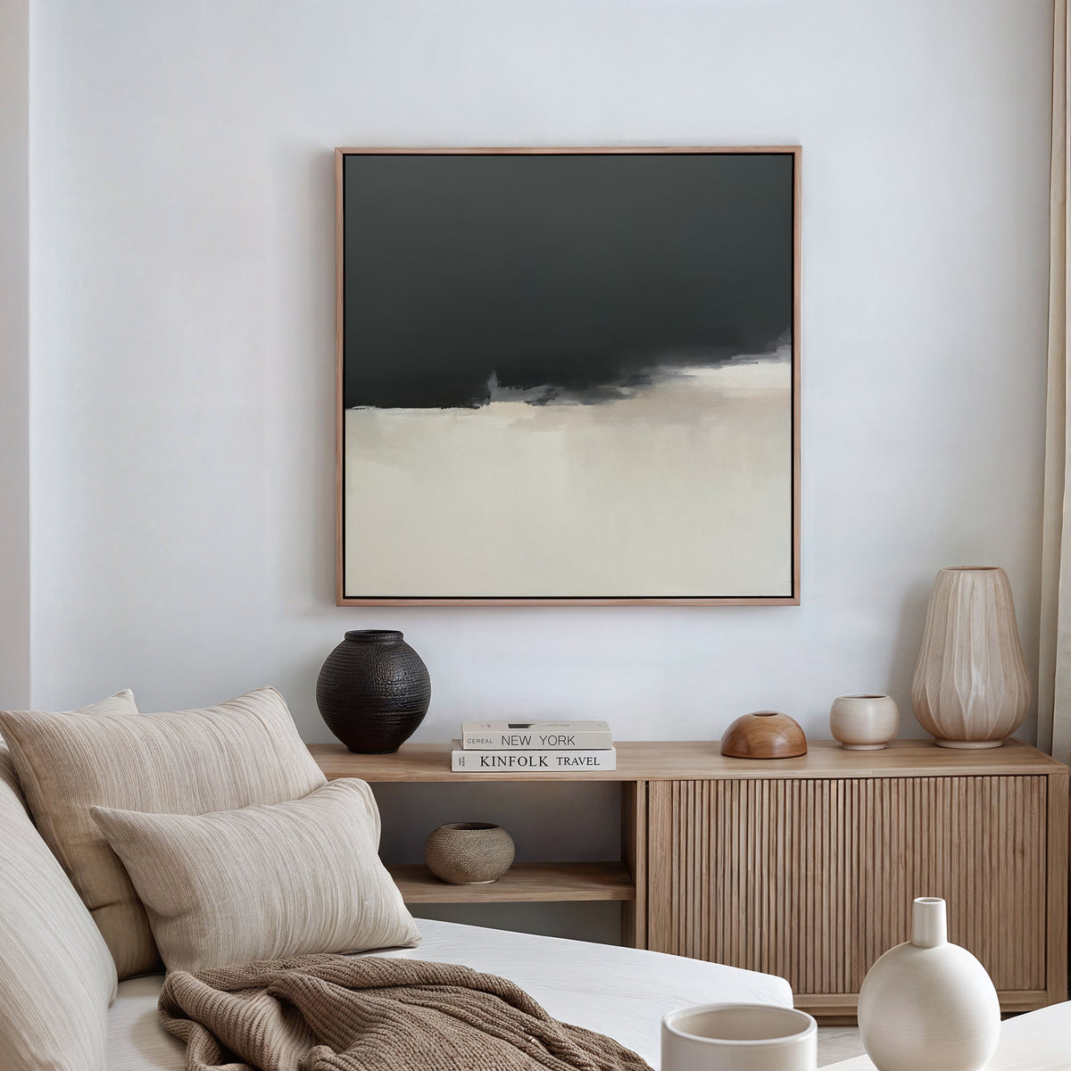 A modern living room featuring a beige sofa, neutral cushions, a wooden sideboard with vases and books, and the Tempest Brewing Canvas Art - Square—a bold abstract painting—serving as a striking focal point.