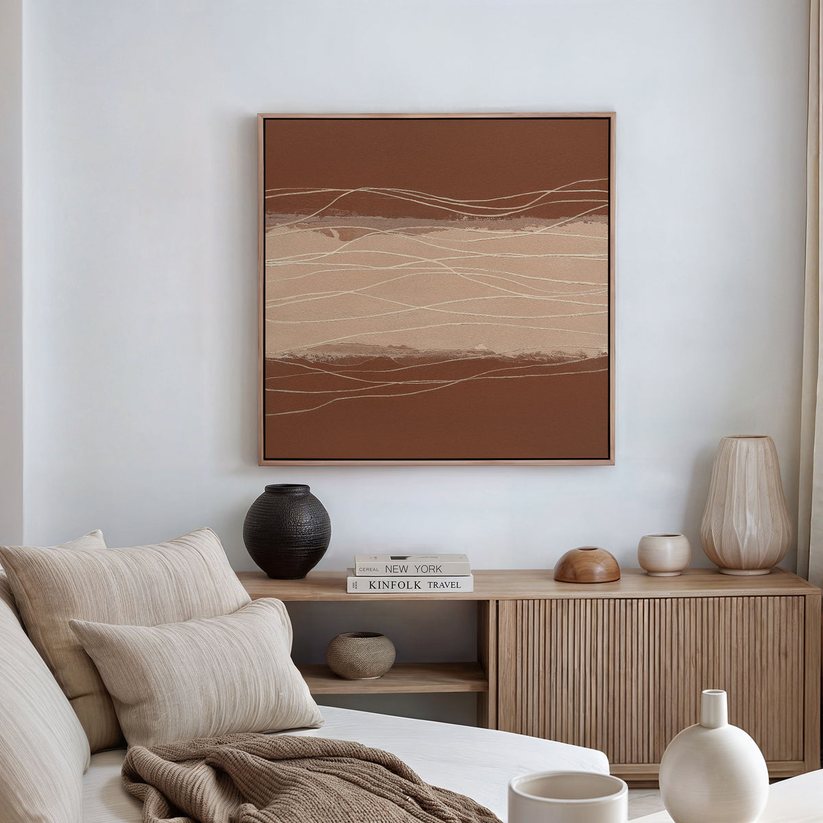 A modern minimalist living room featuring a beige sofa, striped pillows, wooden sideboard, neutral vases, stacked books, and the Terracotta Currents Canvas Art - Square above. The space is styled in earthy, calming tones.