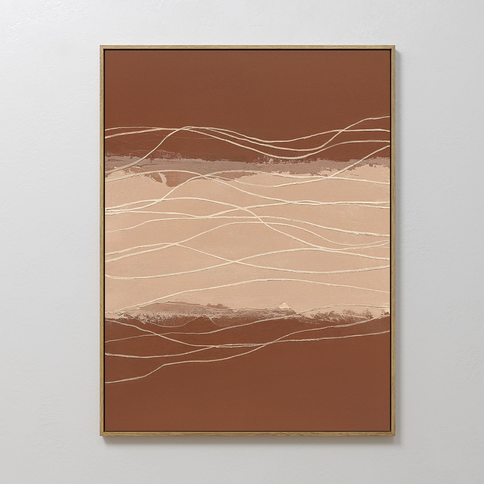 Terracotta Currents Canvas Art - Vertical features abstract wavy lines in beige, cream, and brown, framed in thin gold against a light gray wall. This contemporary print suggests movement—ideal for lovers of terracotta-inspired wall art.