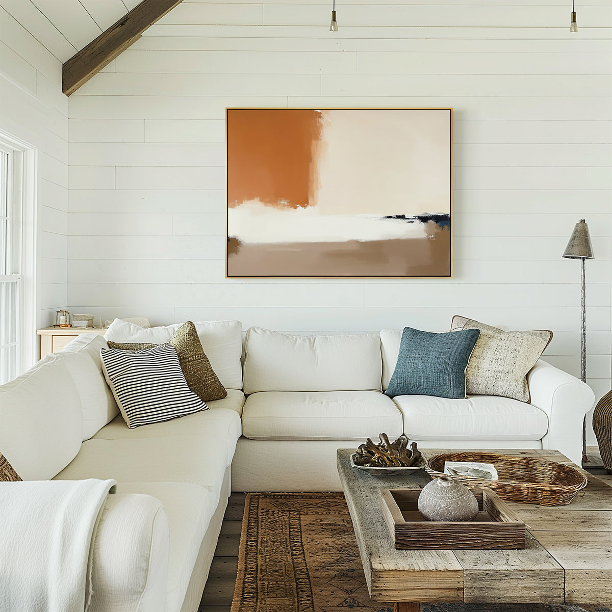 A bright, airy living room with white shiplap walls, a large L-shaped white sofa with textured pillows, a rustic wooden coffee table, and the Terracotta Edge Canvas Art - Horizontal displayed above the couch.