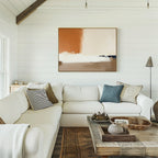 A bright, airy living room with white shiplap walls, a large L-shaped white sofa with textured pillows, a rustic wooden coffee table, and the Terracotta Edge Canvas Art - Horizontal displayed above the couch.