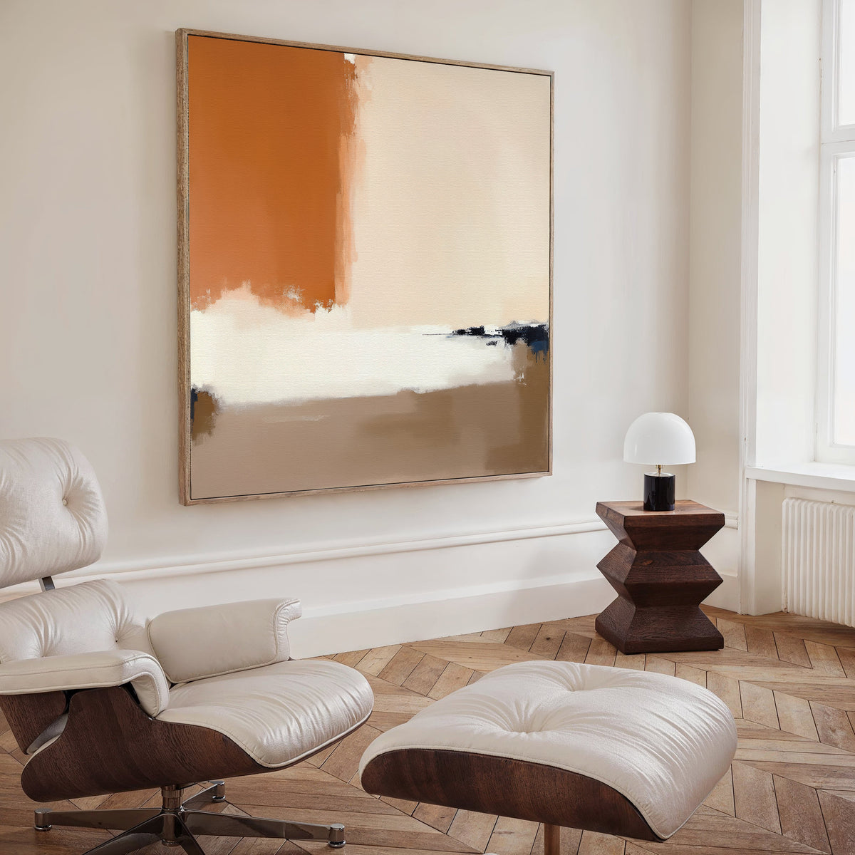 A modern living room features a white leather lounge chair and ottoman, geometric wood side table, and small white lamp by a large window, accented with the Terracotta Edge Canvas Art - Square for striking minimalist decor.