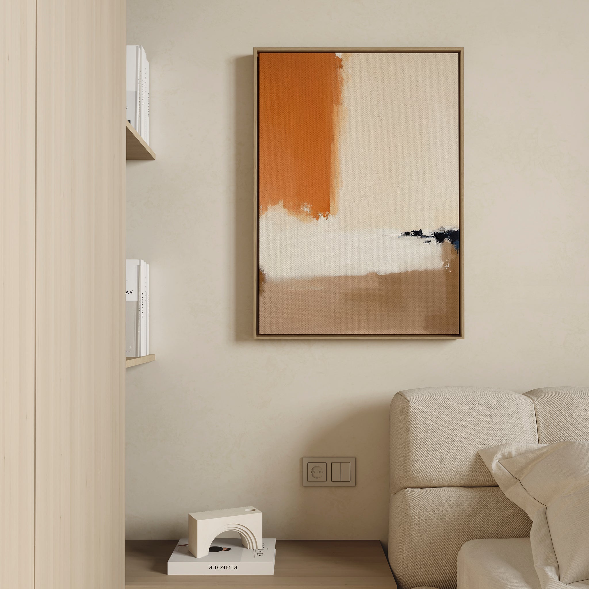 A modern living room decor with a beige sofa, books on a wooden shelf, and the Terracotta Edge Canvas Art - Vertical in orange, beige, and black on a light wall. A small white decorative item rests on the floor.