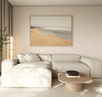 A minimal living room pairs a light beige sectional with a light wood coffee table. Above, the Tidal Meditation Canvas Art - Horizontal adds tranquility. Beige curtains let in natural light, and a leafy plant brings freshness to the corner.