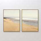 Tidal Meditation - Set of 2 features framed coastal canvas prints displaying serene beach scenes with sandy shores and gentle waves, hung side by side for tranquil decor on any white wall.