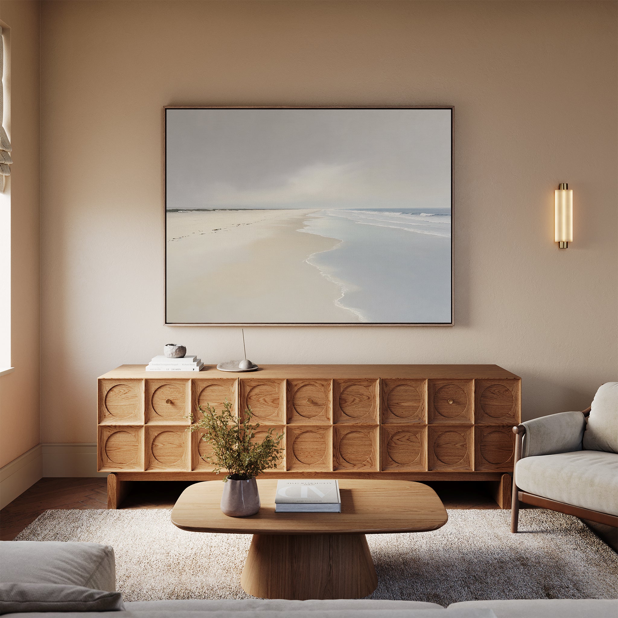 A minimal living room features a beige sofa, wooden coffee table, textured sideboard, and the Tidal Reflections Canvas Art - Horizontal above. A small plant and books add charm, while soft natural light enhances this calming wall decor.