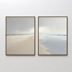 The Tidal Reflections - Set of 2 features framed coastal canvas prints: one highlighting a sandy beach, the other focusing on the shoreline and calm ocean, both displayed side by side for a serene wall art arrangement.
