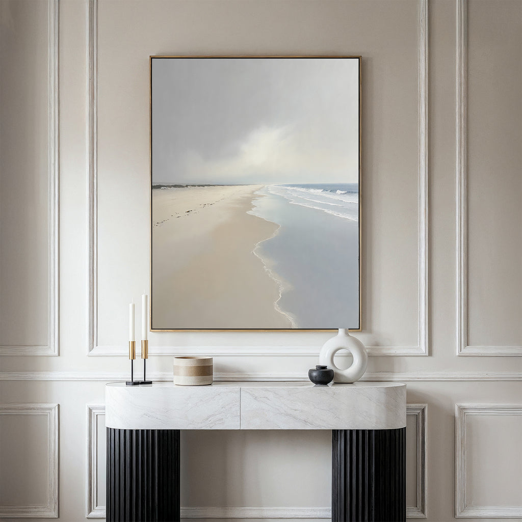 The Tidal Reflections Canvas Art - Vertical hangs on a beige wall above a white marble console table adorned with modern vases and candleholders, depicting a serene ocean scene with calm waves.