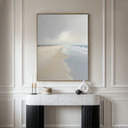 The Tidal Reflections Canvas Art - Vertical hangs on a beige wall above a white marble console table adorned with modern vases and candleholders, depicting a serene ocean scene with calm waves.