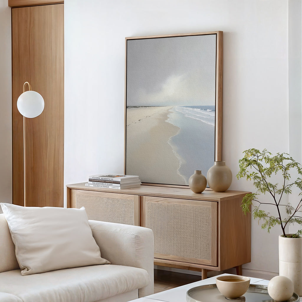 A minimal, modern living room with a light wood sideboard, neutral ceramics, a potted plant, white sofa and cushion, and Tidal Reflections Canvas Art - Vertical as calming wall decor against white walls and wood accents.