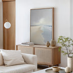 A minimal, modern living room with a light wood sideboard, neutral ceramics, a potted plant, white sofa and cushion, and Tidal Reflections Canvas Art - Vertical as calming wall decor against white walls and wood accents.