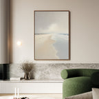 A modern living room with a green curved armchair, Tidal Reflections Canvas Art - Vertical featuring a serene beach scene, a marble shelf, a round wall light, and a vase with dried branches.