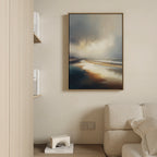 The Tidal Reverie Canvas Art - Vertical, featuring a serene seascape with sunlit water and cloudy skies, hangs above a light sofa in this minimalist living room. White books and a geometric sculpture accent nearby shelves for an elegant coastal feel.
