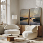 A room with white chairs, a table, and sunset artwork feels warm, while the "Tidal Whispers - Set of 2" coastal marsh wall art adds a serene atmosphere.