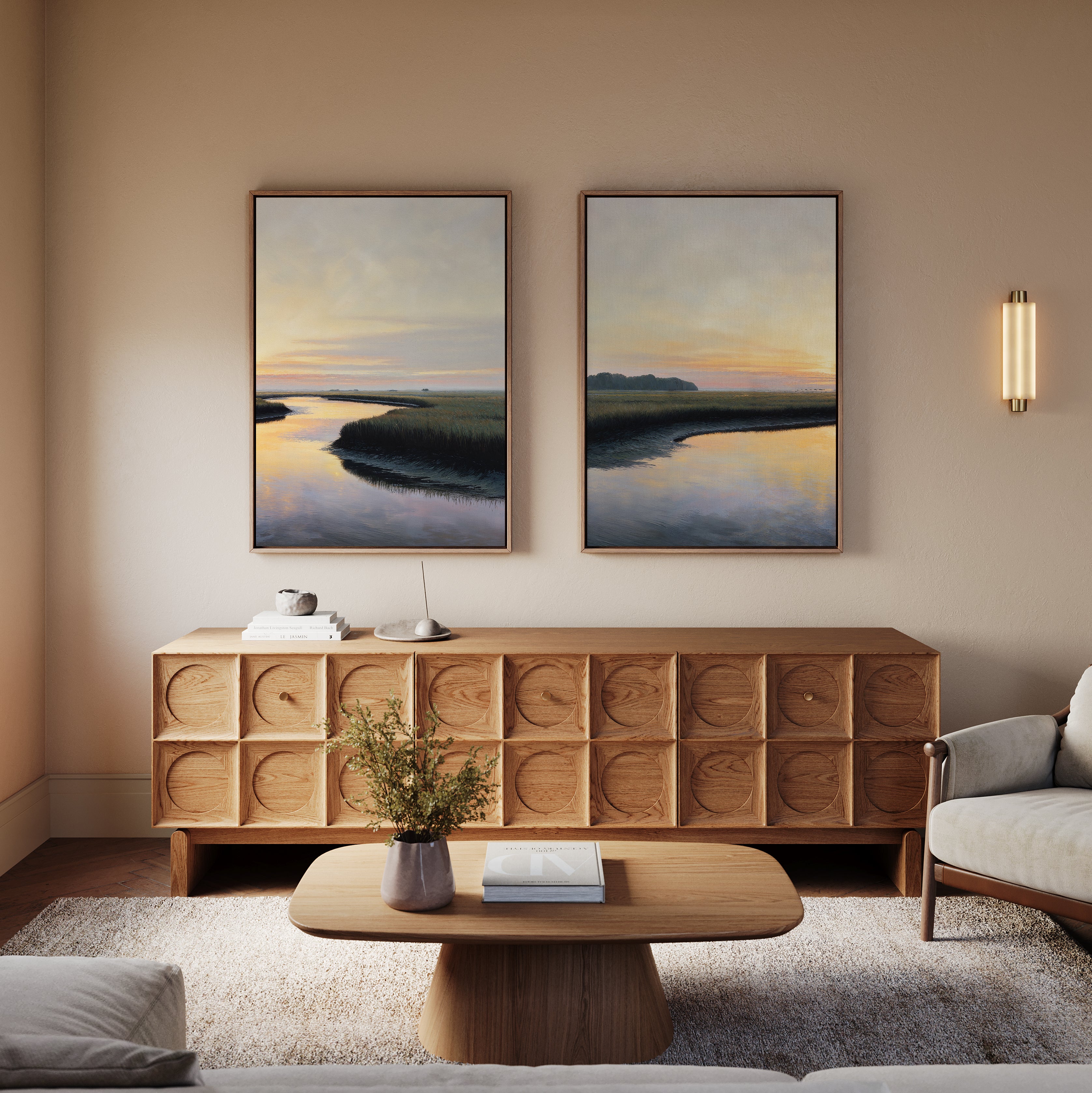 A modern living room with a wooden sideboard, coffee table, and light gray sofa. The "Tidal Whispers - Set of 2" canvas prints and a wall sconce hang above the sideboard, while a small plant and books are on the table.