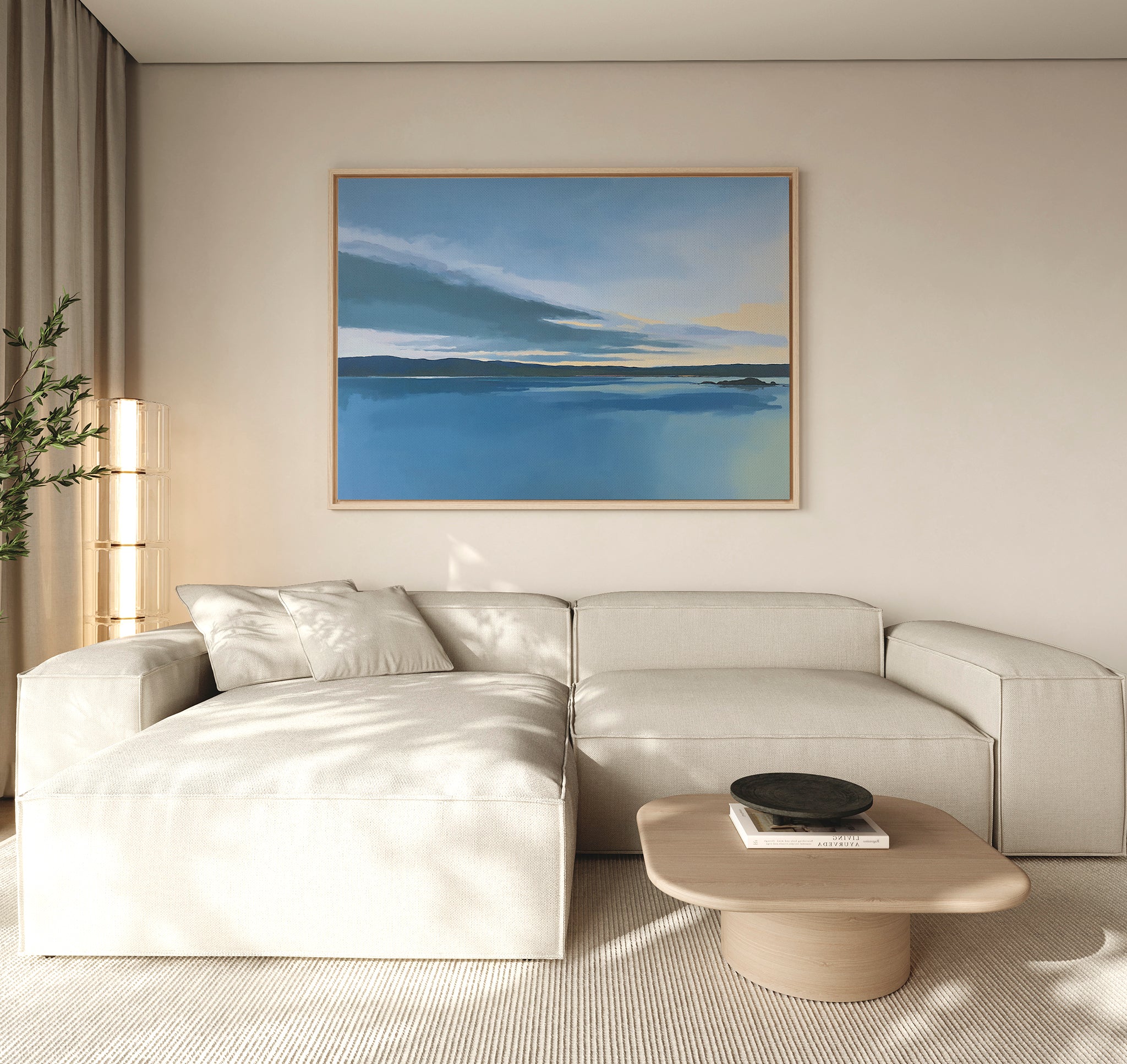 A modern living room with a light beige sectional, wooden coffee table topped with a black bowl, tall plant, and "Tranquil Reflections Canvas Art - Horizontal" depicting water and sky on a neutral wall.