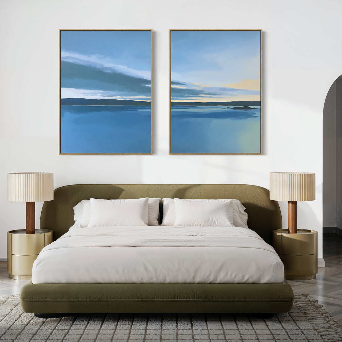 A modern bedroom with a low olive-green bed, white bedding, two gold nightstands with matching lamps, and Tranquil Reflections - Set of 2 artwork above the bed. A gray patterned rug covers the floor.
