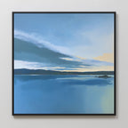 The Tranquil Reflections Canvas Art - Square showcases a calm blue lake with distant hills at sunrise or sunset, featuring soft yellow and blue tones—ideal serene wall art for tranquil bedroom decor on a light-colored wall.
