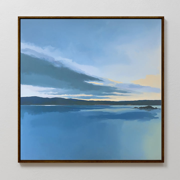 Tranquil Reflections Canvas Art - Square: a framed serene wall art featuring a calm lake under a blue sky with clouds, distant hills, and gentle yellow horizon light—ideal for peaceful bedroom decor.