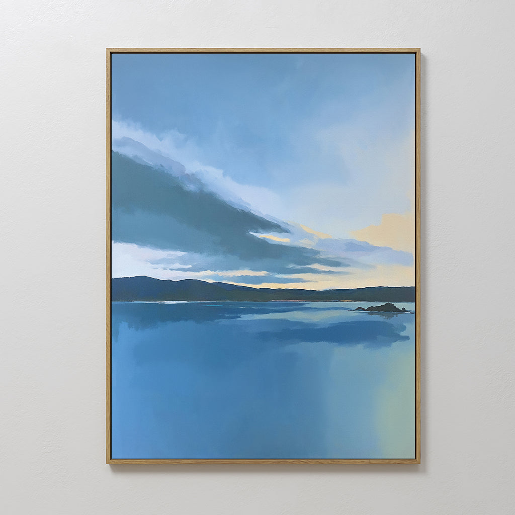 The Tranquil Reflections Canvas Art - Vertical features a serene lakescape with calm blue water, distant dark hills, and a softly tinted sky, beautifully framed and displayed on a plain white wall.