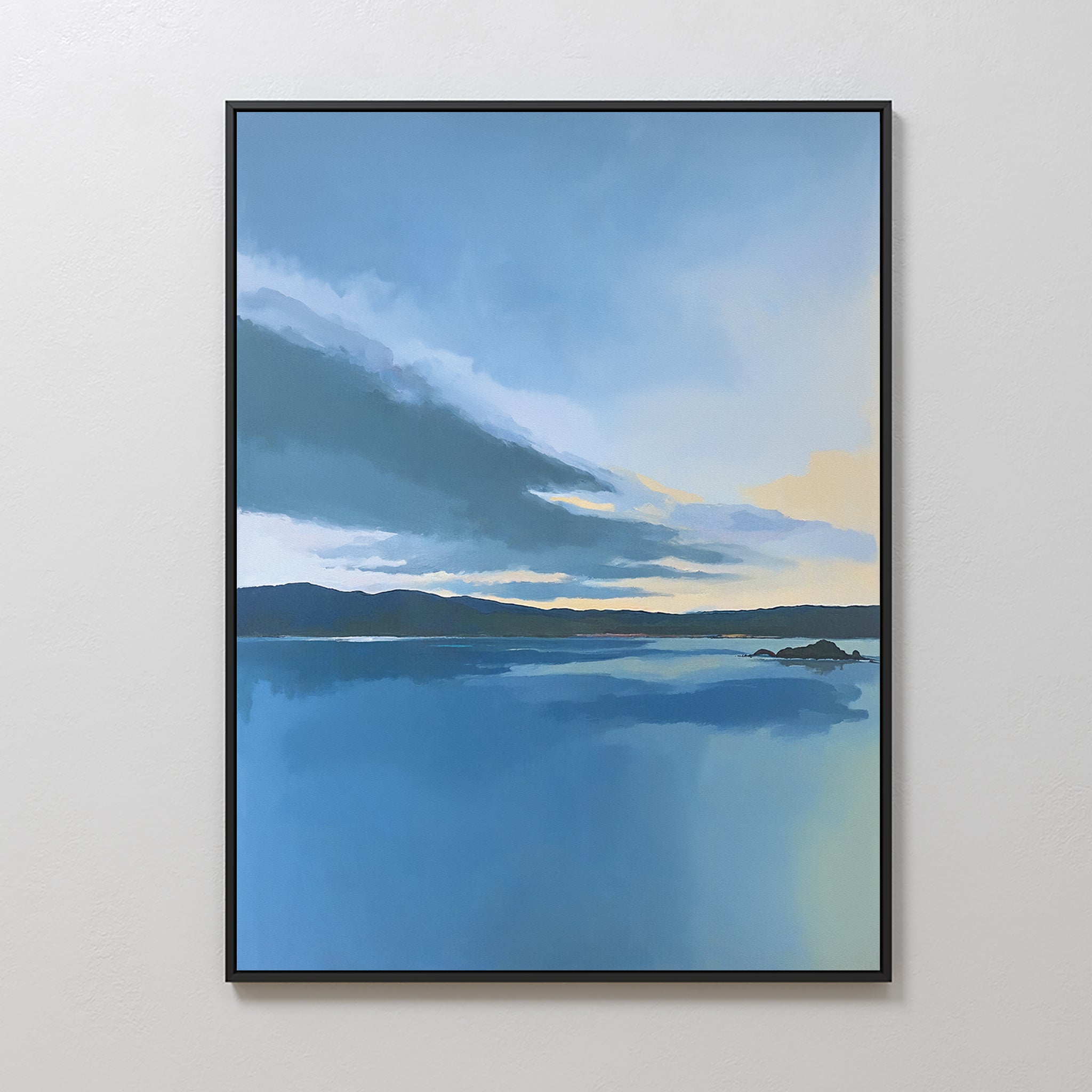 The Tranquil Reflections Canvas Art - Vertical depicts a calm blue lake, distant hills, and a gentle cloudy sky with touches of yellow on the horizon, elegantly displayed on a light-colored wall.