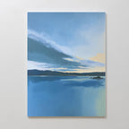 The Tranquil Reflections Canvas Art - Vertical features a serene blue lake mirroring the sky with distant hills and clouds, displayed on a plain white wall.