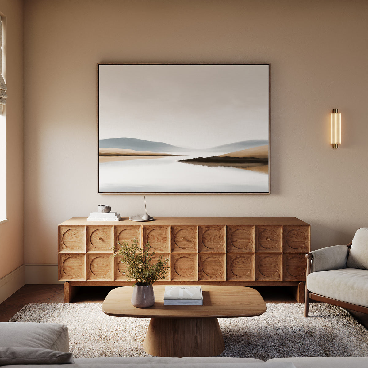 A modern living room with neutral tones features a wooden sideboard, beige sofa, wooden coffee table with books and vase, a soft rug, and the Tranquil Waters Canvas Art - Horizontal displayed on the wall.