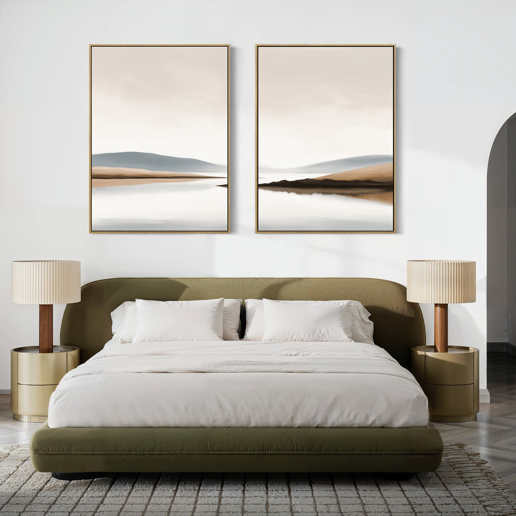 A modern bedroom featuring an olive green upholstered bed, white bedding, beige lamps on round nightstands, a gray textured rug, and "Tranquil Waters - Set of 2" minimalist misty lakeside landscape canvas prints above the bed.