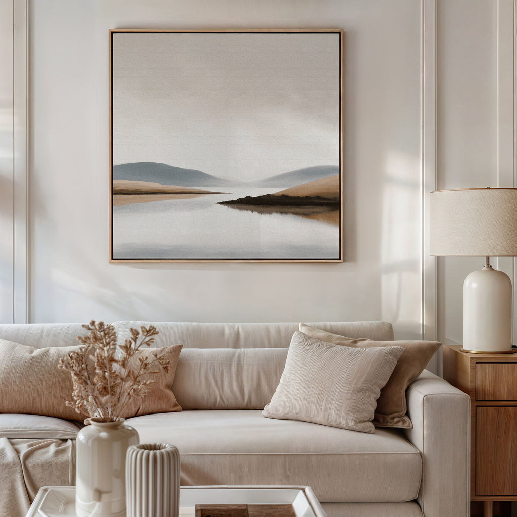A modern living room features a beige sofa with neutral cushions, a side table with a lamp, and the Tranquil Waters Canvas Art - Square hanging above. A vase of dried flowers on the coffee table completes the stylish decor.