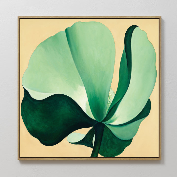 The Tropical Serenity Canvas Art - Square is a framed beige canvas print with a large abstract green flower, its smooth petals layered over a soft background—an ideal touch of subtle coastal decor for light-colored walls.
