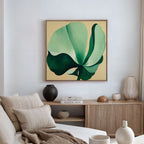 A modern living room includes a neutral sofa with beige pillows, a wooden sideboard with books and decor, and the Tropical Serenity Canvas Art - Square as the focal point for coastal wall decor.