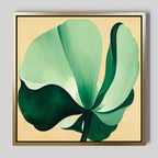 Tropical Serenity Canvas Art - Square features a large, abstract green flower with broad petals on soft beige canvas in a gold and black-edged frame—an elegant choice for coastal wall decor.