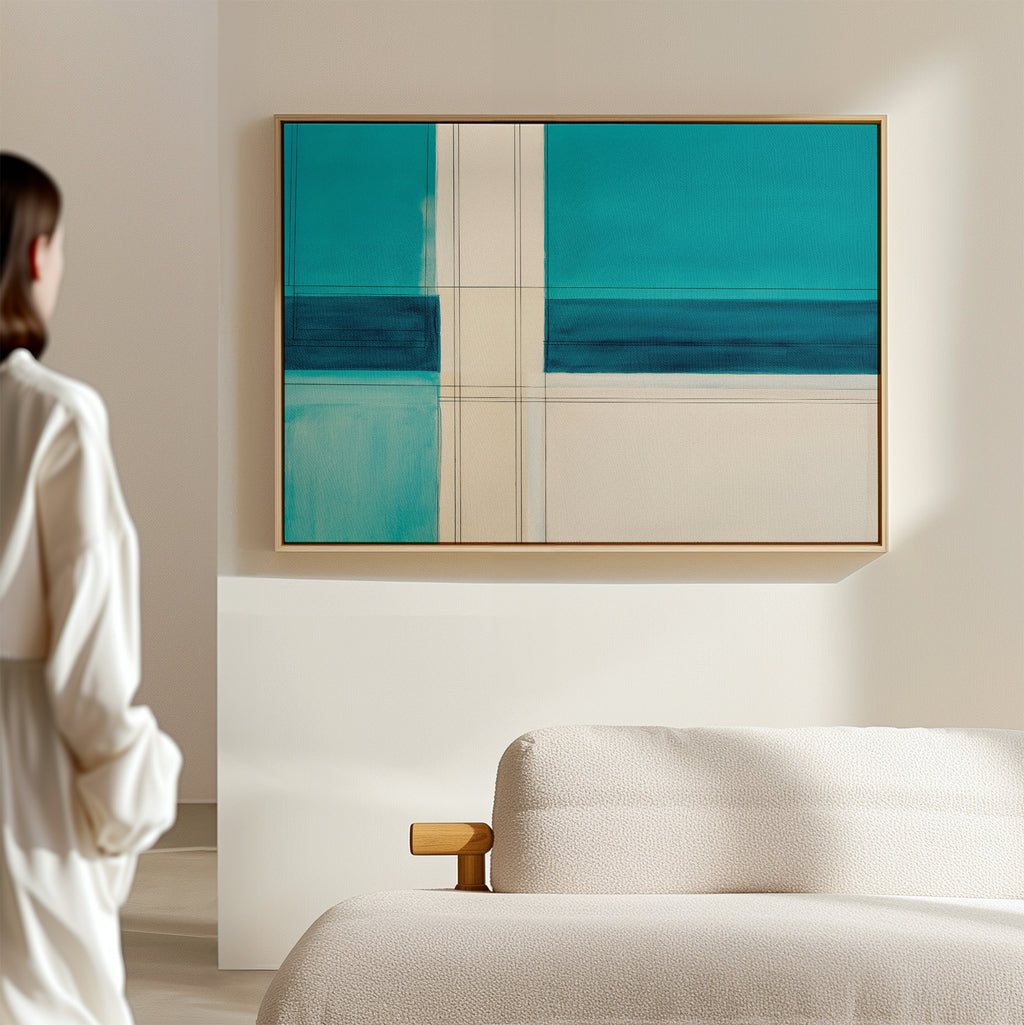 A person stands in a modern living room, admiring the Turquoise Grid Canvas Art - Horizontal, a contemporary abstract piece with geometric patterns, displayed above a light-colored sofa.
