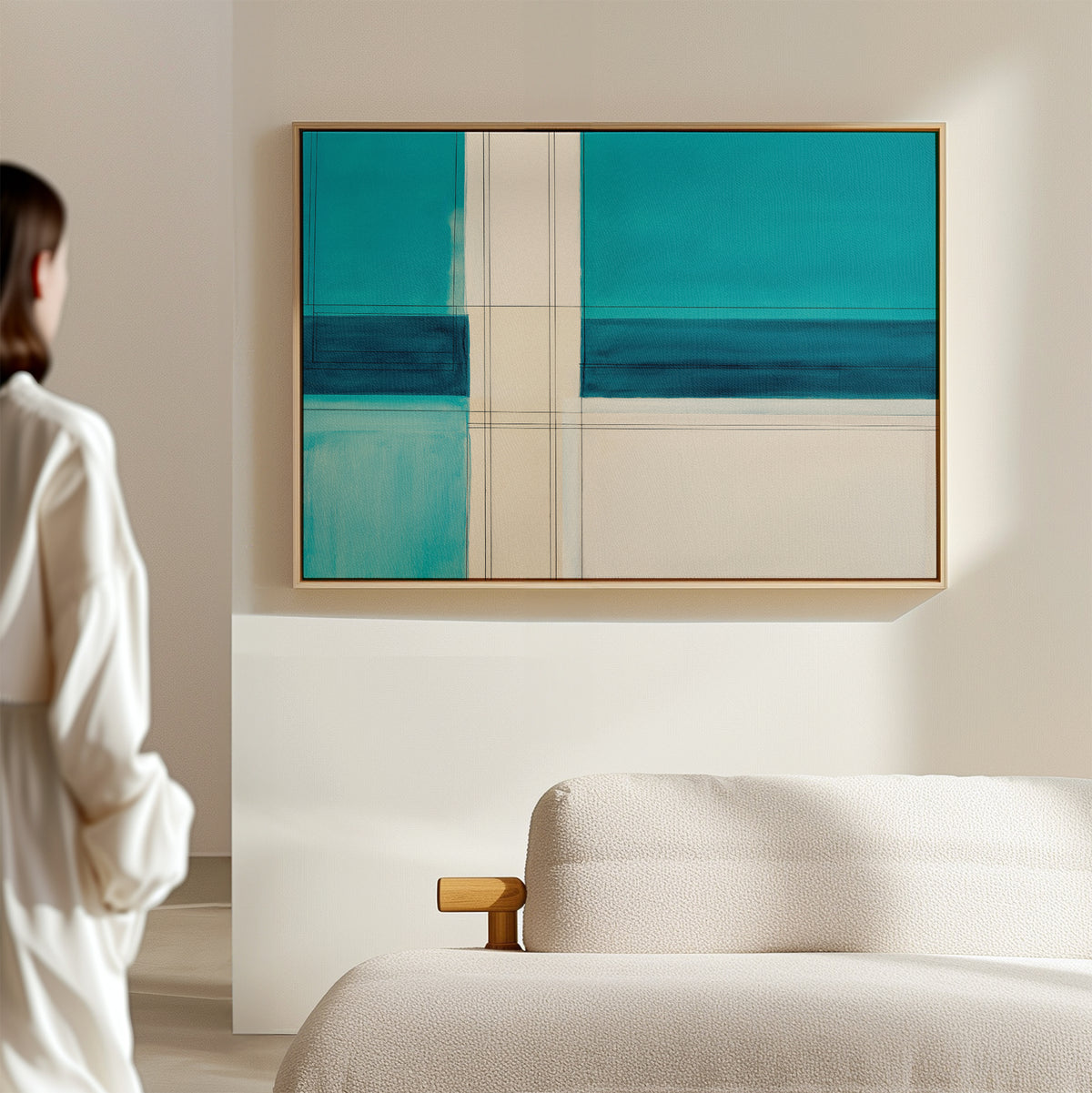 A person stands in a modern living room, admiring the Turquoise Grid Canvas Art - Horizontal, a contemporary abstract piece with geometric patterns, displayed above a light-colored sofa.