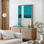 A modern living room with a light wood sideboard, Turquoise Grid Canvas Art - Vertical above it, ceramic vases, stacked books, white sofa and cushion, round lamp, and a small potted plant.