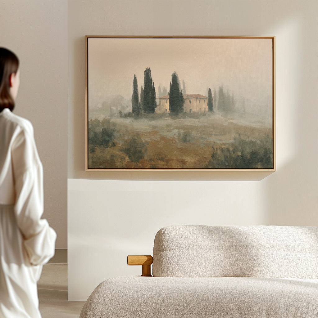A person in a white robe admires the Tuscan Veil Canvas Art—hung above a beige sofa on a light wall—in a minimal, modern room.